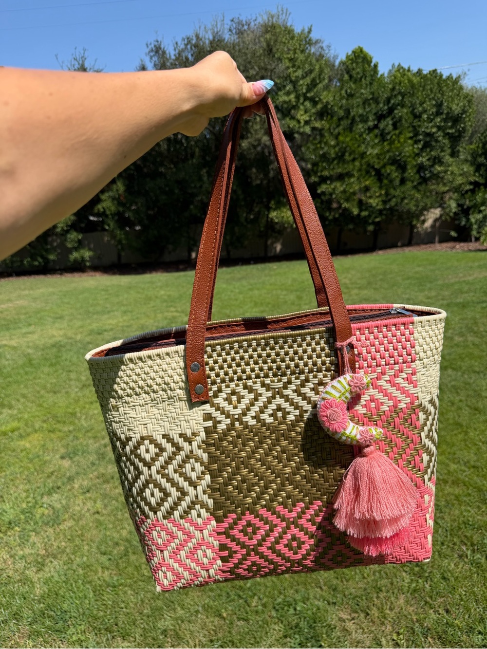 Woven Straw Tote Bag with Brown Leather Handles and Pink Tassel Accent